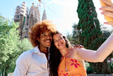 Fototapeta Londyn - multiethnic couple of tourists visiting Barcelona, Spain and taking selfie