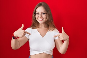 Sticker - Young caucasian woman standing over red background looking confident with smile on face, pointing oneself with fingers proud and happy.