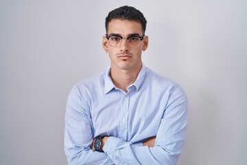 Canvas Print - Handsome hispanic man wearing business clothes and glasses skeptic and nervous, disapproving expression on face with crossed arms. negative person.