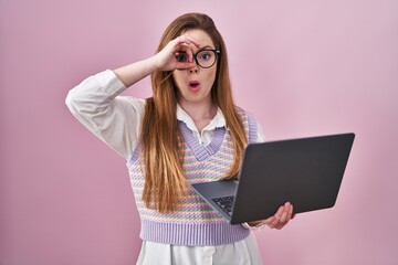 Wall Mural - Young caucasian woman working using computer laptop doing ok gesture shocked with surprised face, eye looking through fingers. unbelieving expression.