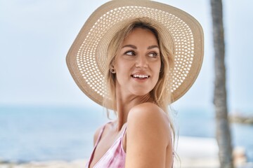 Wall Mural - Young blonde woman tourist smiling confident standing at seaside