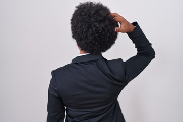 Poster - Beautiful african woman with curly hair wearing business jacket and glasses backwards thinking about doubt with hand on head