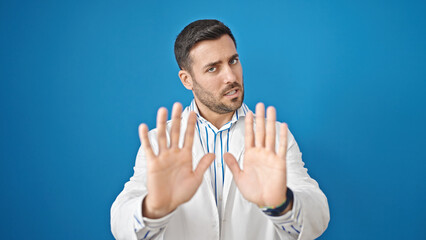 Poster - Young hispanic man doctor doing wait expression with hands over isolated blue background