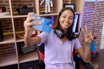 Wall Mural - Young african american woman streamer smiling confident make selfie by smartphone at gaming room