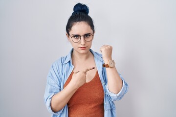 Poster - Young modern girl with blue hair standing over white background in hurry pointing to watch time, impatience, looking at the camera with relaxed expression