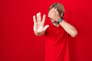 Poster - Caucasian man with mustache standing over red background covering eyes with hands and doing stop gesture with sad and fear expression. embarrassed and negative concept.