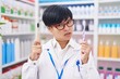 Young asian woman with short hair doing toothbrush comparative at pharmacy in shock face, looking skeptical and sarcastic, surprised with open mouth
