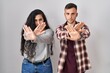 © Krakenimages.com - Young hispanic couple standing over white background rejection expression crossing arms and palms doing negative sign, angry face