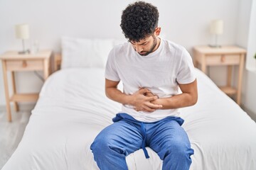 Canvas Print - Young arab man suffering for stomachache sitting on bed at bedroom