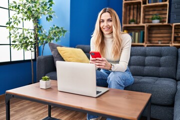 Sticker - Young blonde woman using smartphone and laptop at home