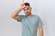 © Krakenimages.com - Hispanic man with beard standing over white background making fun of people with fingers on forehead doing loser gesture mocking and insulting.