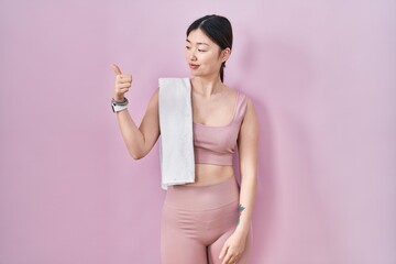 Canvas Print - Chinese young woman wearing sportswear and towel looking proud, smiling doing thumbs up gesture to the side