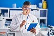 © Krakenimages.com - Young latin man scientist smiling confident using touchpad at laboratory