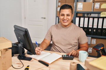 Sticker - Young latin man ecommerce business worker using calculator writing on notebook at office