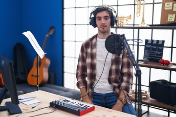 Canvas Print - Young hispanic man playing piano at music studio with serious expression on face. simple and natural looking at the camera.