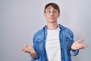 Poster - Caucasian blond man standing wearing glasses clueless and confused with open arms, no idea concept.