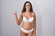 © Krakenimages.com - Young hispanic woman wearing white lingerie showing and pointing up with fingers number two while smiling confident and happy.