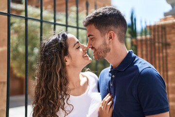 Young hispanic couple smiling confident hugging each other and kissing at street