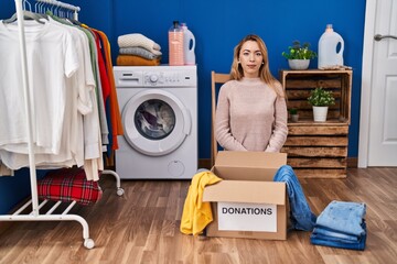 Canvas Print - Hispanic woman putting clothes in donation box with serious expression on face. simple and natural looking at the camera.