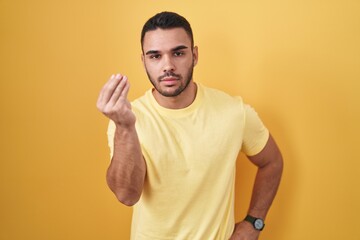 Canvas Print - Young hispanic man standing over yellow background doing italian gesture with hand and fingers confident expression