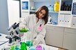 © Krakenimages.com - Young beautiful hispanic woman scientist smiling confident pouring liquid on test tube at laboratory