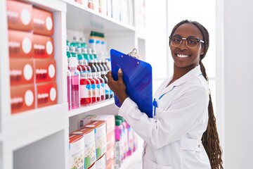 Sticker - African american woman pharmacist writing on document at pharmacy