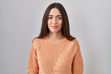 Poster - Young brunette woman standing over white background relaxed with serious expression on face. simple and natural looking at the camera.