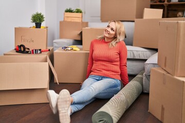 Canvas Print - Young blonde woman smiling confident sitting on floor at new home