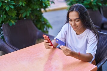 Sticker - Young beautiful hispanic woman using smartphone and credit card sitting on table at coffee shop terrace