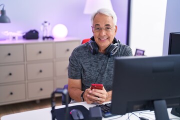 Wall Mural - Middle age grey-haired man streamer using computer and smartphone at gaming room