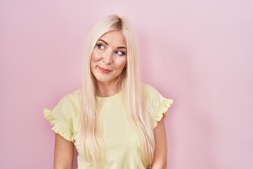 Sticker - Caucasian woman standing over pink background smiling looking to the side and staring away thinking.