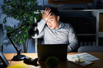 Canvas Print - Young chinese man working using computer laptop at night surprised with hand on head for mistake, remember error. forgot, bad memory concept.