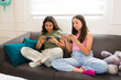 Teen girls using their phone while hanging out on the sofa
