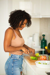 Wall Mural - young african american woman cutting food in kitchen