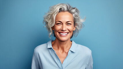 smiling attractive woman 50s years old look to the camera, isolated on plain blue background studio 