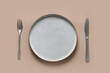 Empty gray plate on beige culinary background. Kitchen and cooking template, mock up. View from above.