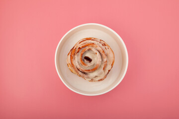 Homemade baked cinnabon rolls with cinnamon and icing on white plate, top view. Sweet traditional dessert bun for breakfast