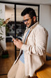 © Drobot Dean - Young indian business man using smartphone while standing in office