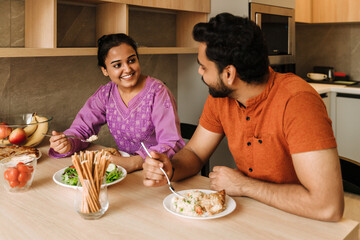 Happy indian couple eating together at home