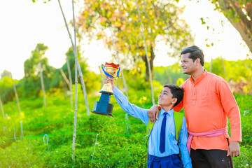 Wall Mural - Happy indian farmer son showing trophy 