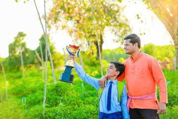 Wall Mural - Cute indian farmer child in school uniform with his father at agriculture field