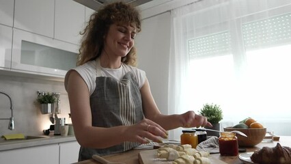 Wall Mural - happy young adult caucasian woman prepare croissants in the kitchen