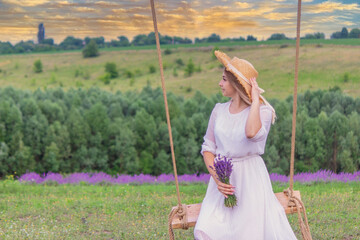 Wall Mural - girl on a swing in a field of lavender. Selective focus