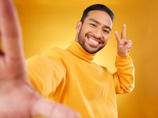 Sticker - Selfie, peace sign and happy portrait of a man in studio with hand, emoji and a smile. Male asian fashion model on a yellow background with a positive mindset for social media profile picture update