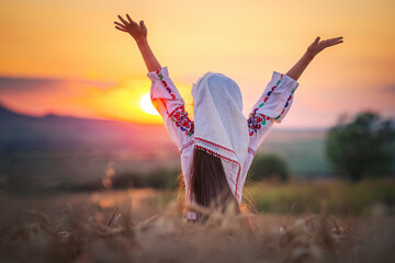 Wall Mural - Farmer woman bulgarian little girl in ethnic folklore costume hold golden wheat straws and sickle in harvest field, harvesting and agriculture in Bulgaria