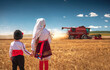 © ValentinValkov - Bulgarian girl and boy with traditional folklore costume at the agricultural wheat field during harvest time with industrial combine machine