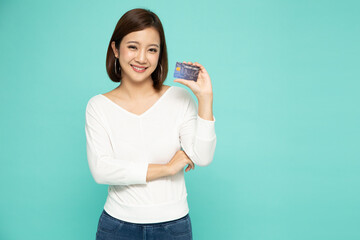 Young Asian woman smiling, showing, presenting credit card for making payment or paying online isolated on green background