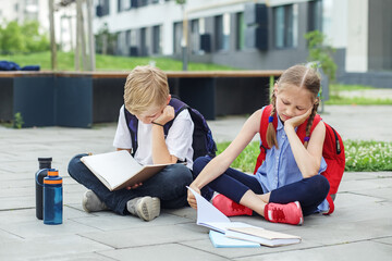 Wall Mural - Schoolchildren are bored reading books and studying homework in school yard. Mental health.