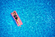 © artiemedvedev - Fit pretty girl in bikini chilling on inflatable pink mattress in swimming pool. Slim hot woman in swimwear tanning. Female relaxing on float in blue water at luxury resort. Aerial, view from above.