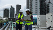 © naraichal - Male and Female engineer team working on the rooftop of a high building in City